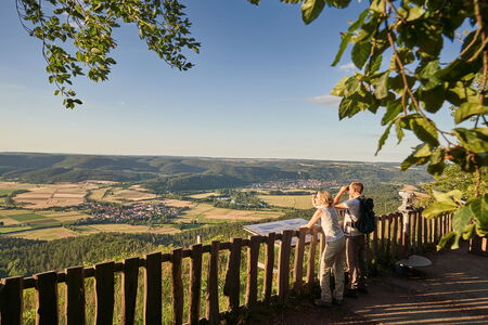 Ein Wanderpaar genießt den Ausblick vom Heldrastein ins Werratal bis weit ins Eichsfeld.
